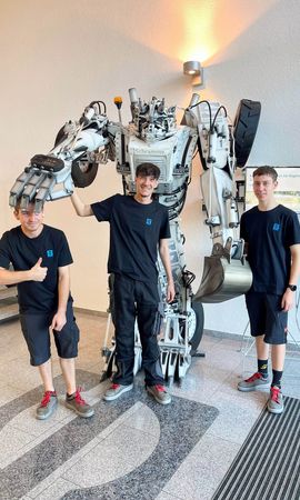 Auszubildende in der Eingangshalle vor dem Roboter SAM bei Magnetbau Schramme 